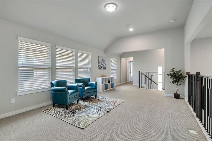 Sitting room with light colored carpet and vaulted ceiling