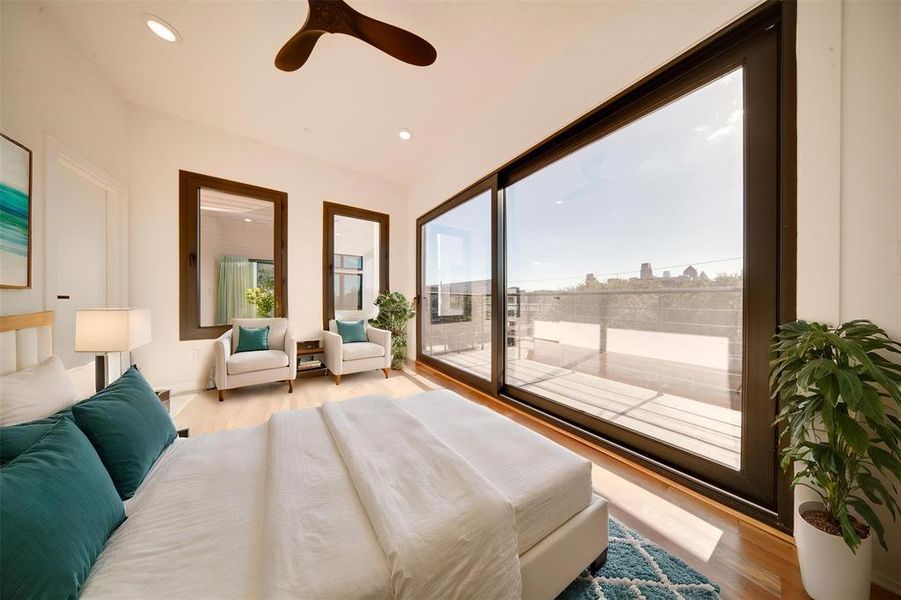 Bedroom with ceiling fan, light hardwood / wood-style flooring, multiple windows, and access to exterior