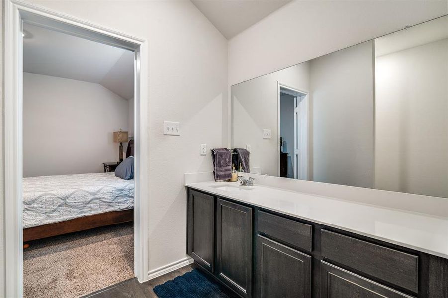 Bathroom featuring hardwood / wood-style floors, vanity, and vaulted ceiling