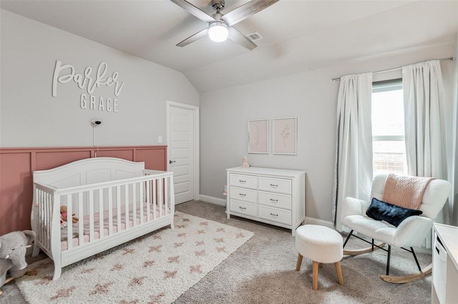 Bedroom featuring carpet flooring, lofted ceiling, a crib, and ceiling fan