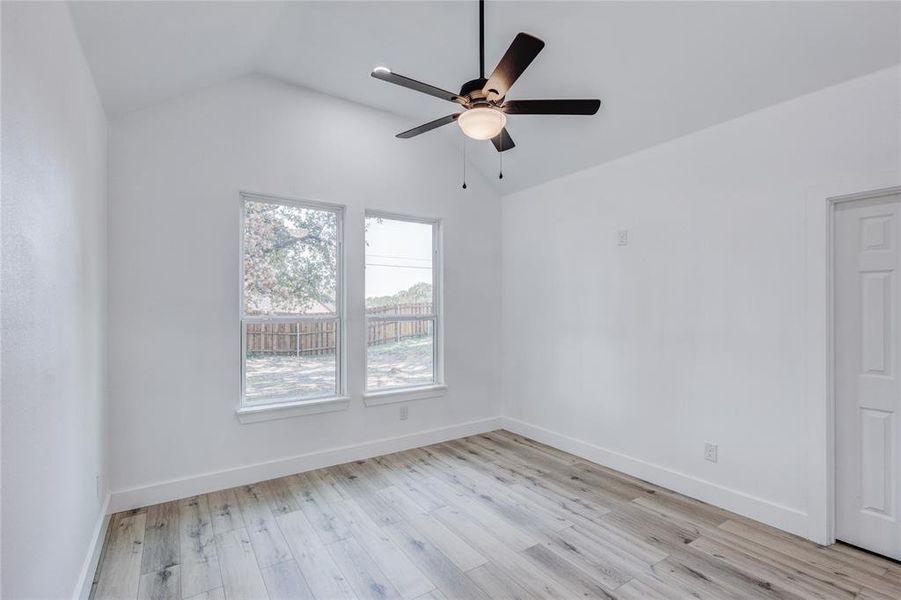 Spare room featuring ceiling fan, lofted ceiling, and light hardwood / wood-style floors