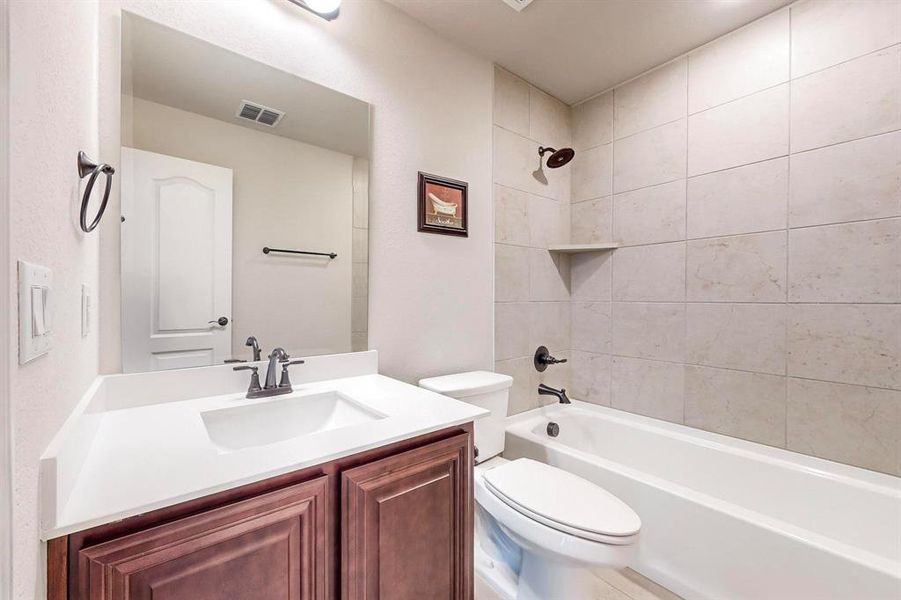 Full bathroom featuring vanity, toilet, and tiled shower / bath combo