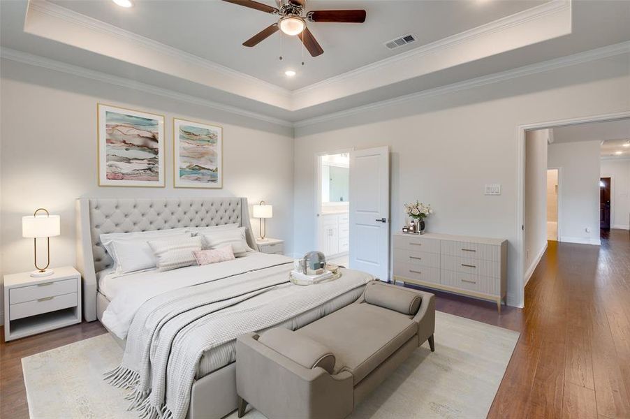 Bedroom featuring crown molding, a tray ceiling, and wood-type flooring