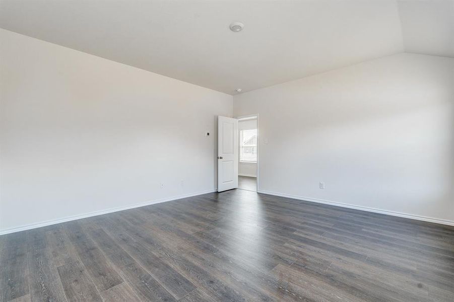 Spare room featuring lofted ceiling and dark hardwood / wood-style flooring