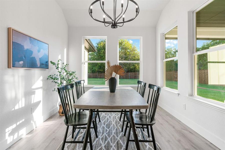 Dining room with an inviting chandelier, light hardwood / wood-style flooring, and vaulted ceiling