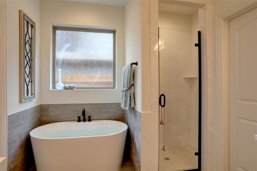 Bathroom with a wealth of natural light, tile walls, and shower with separate bathtub