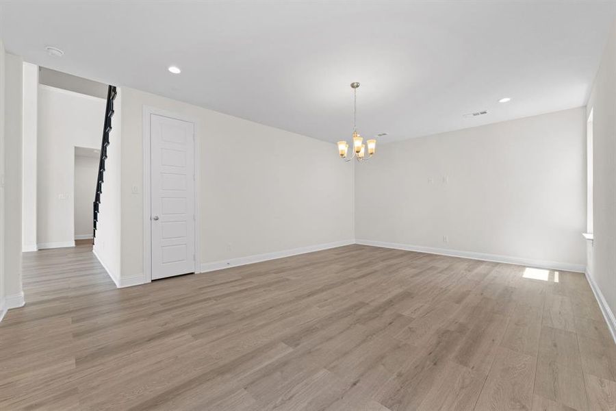 Unfurnished room with a notable chandelier, light hardwood / wood-style floors, and a barn door