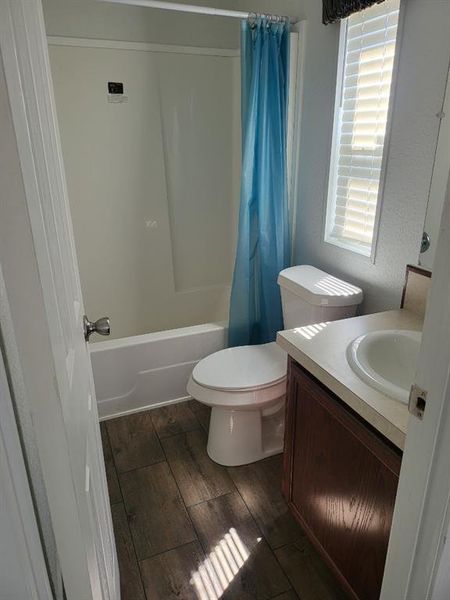 Full bathroom with vanity, toilet, shower / bath combination with curtain, and hardwood / wood-style floors