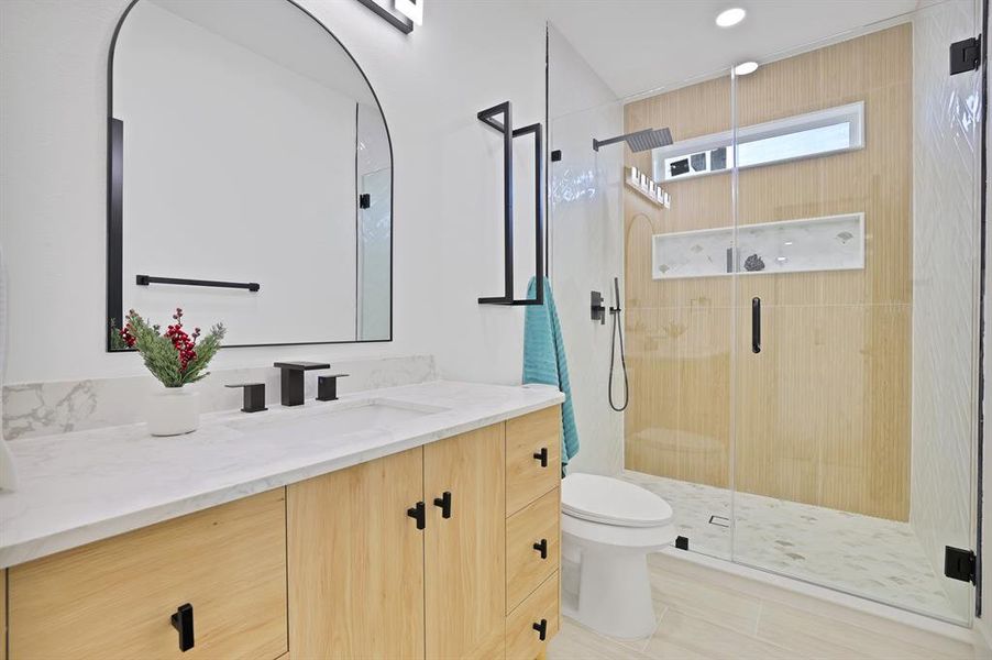 Bathroom with vanity, a shower with shower door, and toilet