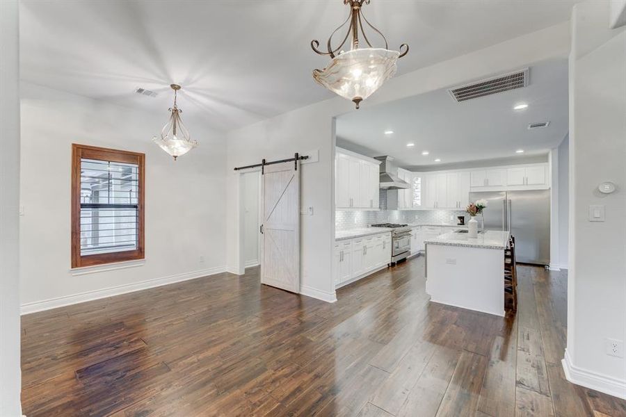 Another view of the open-concept living and kitchen space featuring a center island and a sliding barn door that adds character to the room.