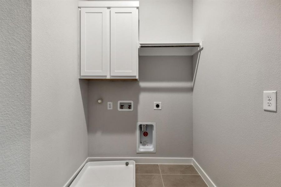 Laundry area with tile patterned flooring, hookup for a gas dryer, cabinets, hookup for an electric dryer, and washer hookup