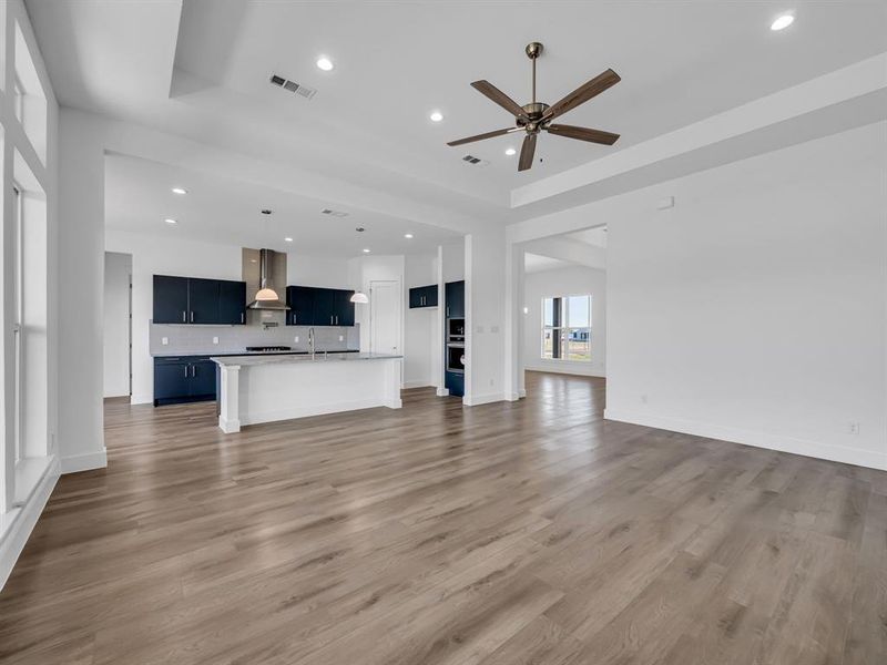 Unfurnished living room featuring hardwood / wood-style floors, sink, a tray ceiling, and ceiling fan