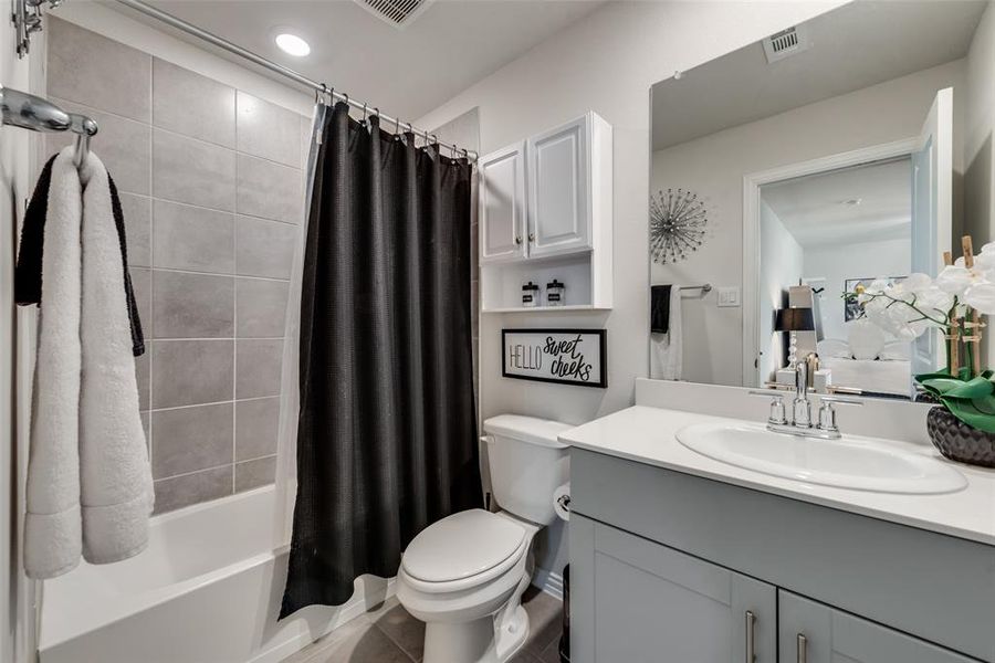 Full bathroom with shower / bath combo with shower curtain, vanity with extensive cabinet space, tile flooring, and toilet