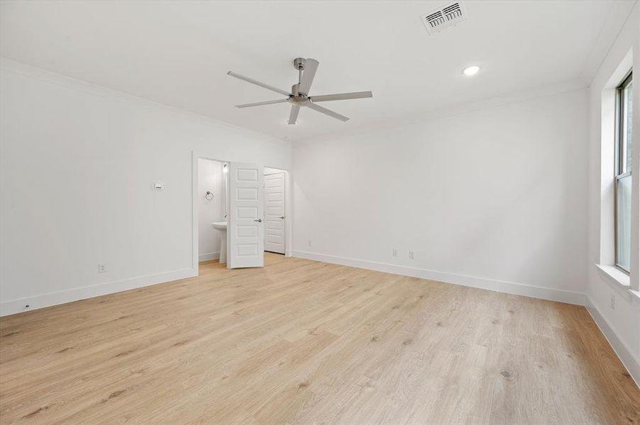 Unfurnished bedroom featuring light hardwood / wood-style floors, connected bathroom, crown molding, and ceiling fan