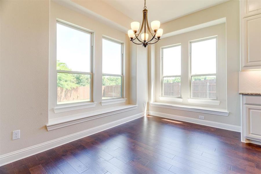 Unfurnished dining area with dark hardwood / wood-style floors and an inviting chandelier