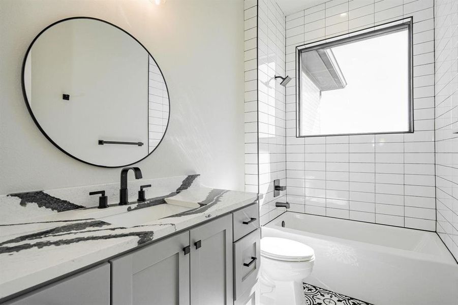 Example of builders Full bathroom featuring toilet, vanity, and tiled shower / bath combo