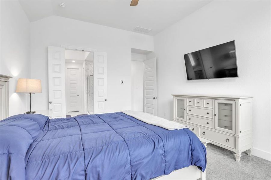 Carpeted bedroom with ceiling fan and vaulted ceiling