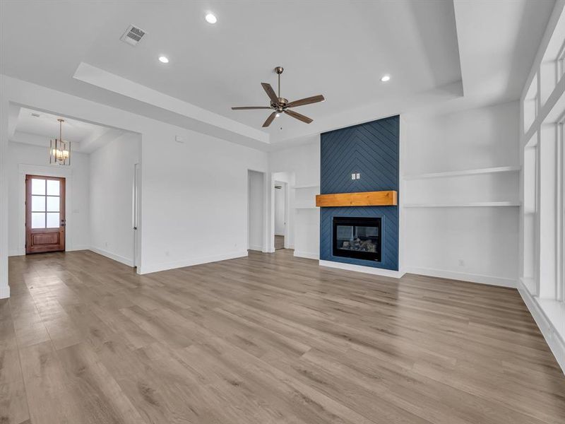 Unfurnished living room featuring light hardwood / wood-style flooring, a fireplace, and a raised ceiling