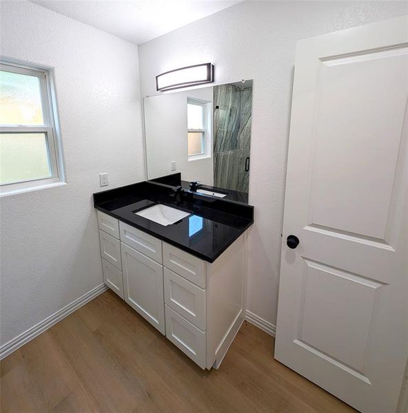 Bathroom featuring a shower with door, hardwood / wood-style floors, and vanity