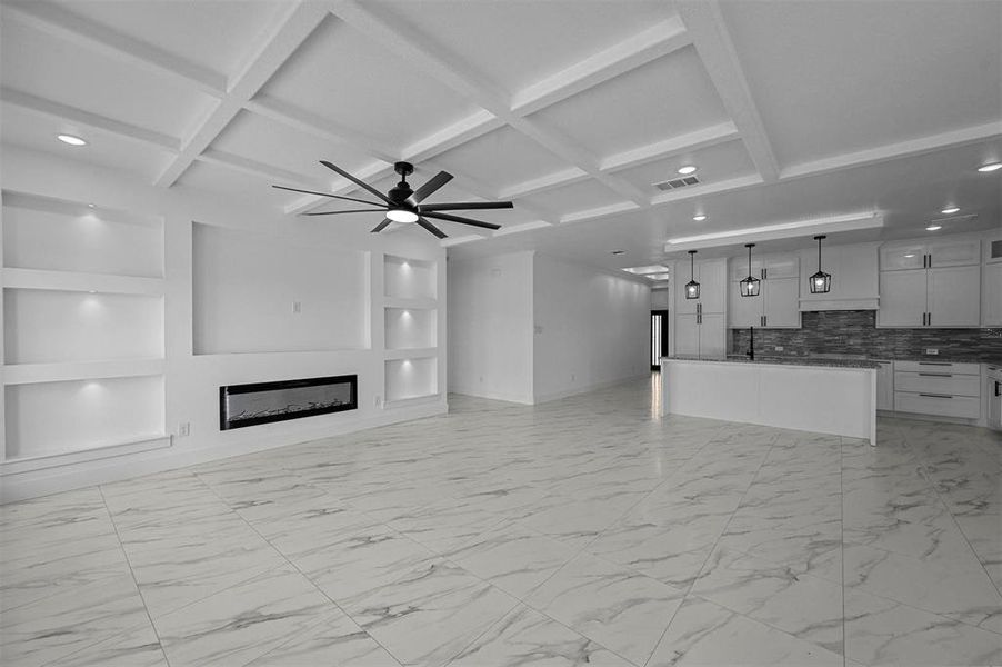 Unfurnished living room featuring beam ceiling, coffered ceiling, light tile patterned floors, and ceiling fan