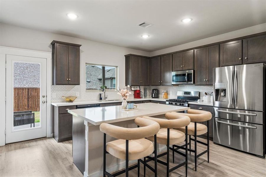 Kitchen featuring a breakfast bar, a healthy amount of sunlight, stainless steel appliances, and a kitchen island