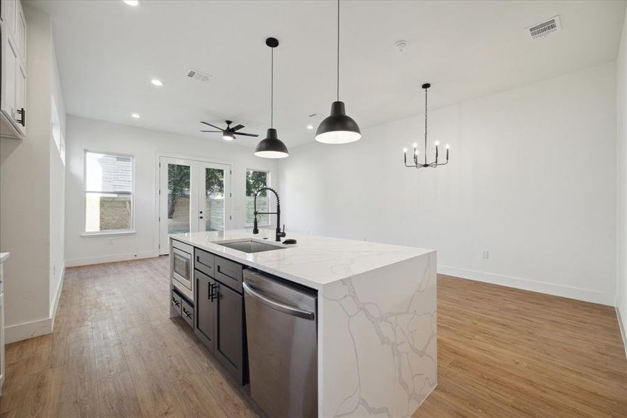 The kitchen features a large island with breakfast bar, tile backsplash, and white cabinets.