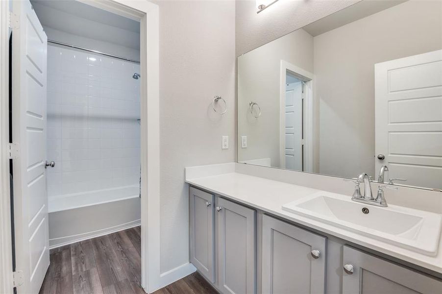 Bathroom featuring vanity, shower / bath combination, and wood-type flooring