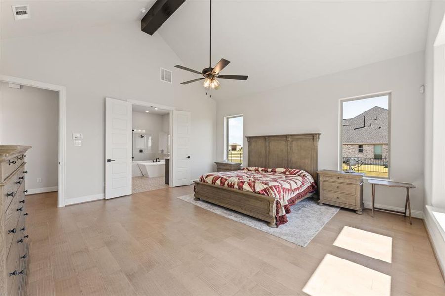 Bedroom featuring ceiling fan, beamed ceiling, high vaulted ceiling, light wood-type flooring, and ensuite bathroom