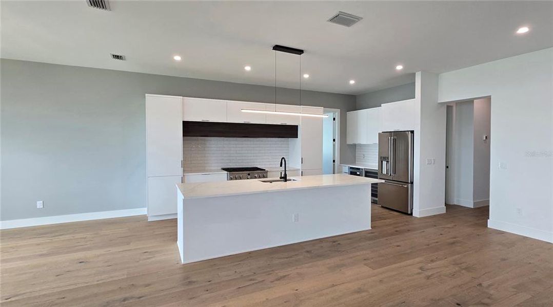 Hallway from the Kitchen leads to the Powder Room, Two Guest suites and the Attached Garage.