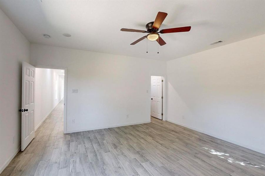 Secondary bedroom with light wood-type flooring and ceiling fan