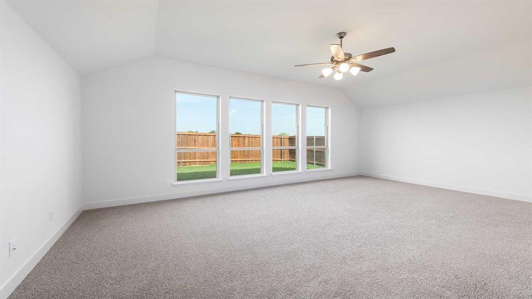 Carpeted empty room with lofted ceiling and ceiling fan