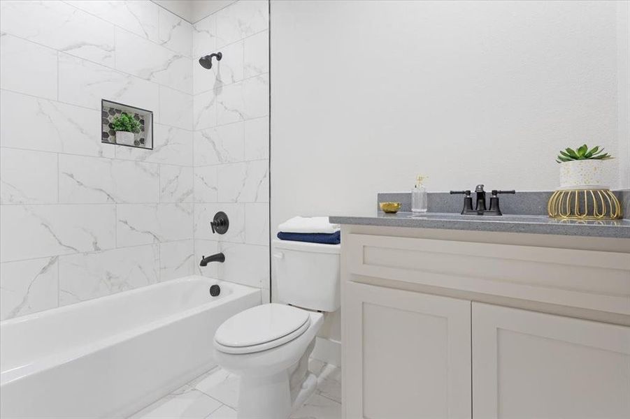 Full bathroom featuring tiled shower / bath, vanity, toilet, and tile floors