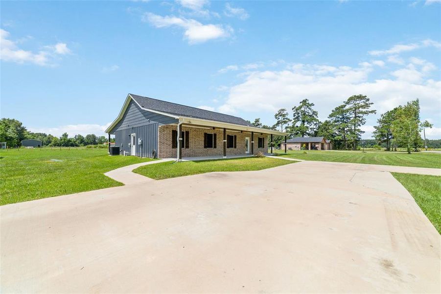 From the side of the home, a gracefully paved walkway leads to a covered front porch area, offering a perfect spot to welcome guests and ample space for outdoor furniture to relax and enjoy the beautiful surroundings.