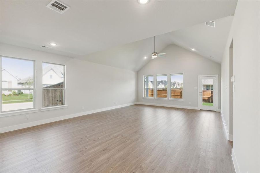 Unfurnished living room featuring lofted ceiling, light hardwood / wood-style flooring, and ceiling fan