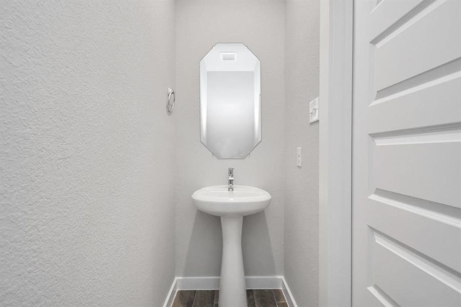 Step into this bright and airy half bath, where a sleek pedestal sink and modern hardware elevate the space with contemporary charm.