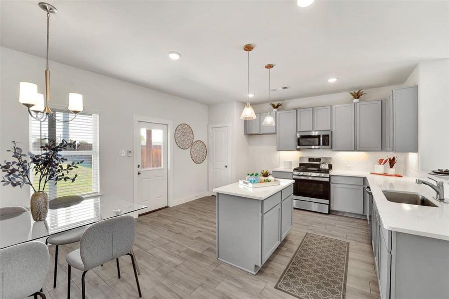 Kitchen with decorative light fixtures, gray cabinets, appliances with stainless steel finishes, and sink