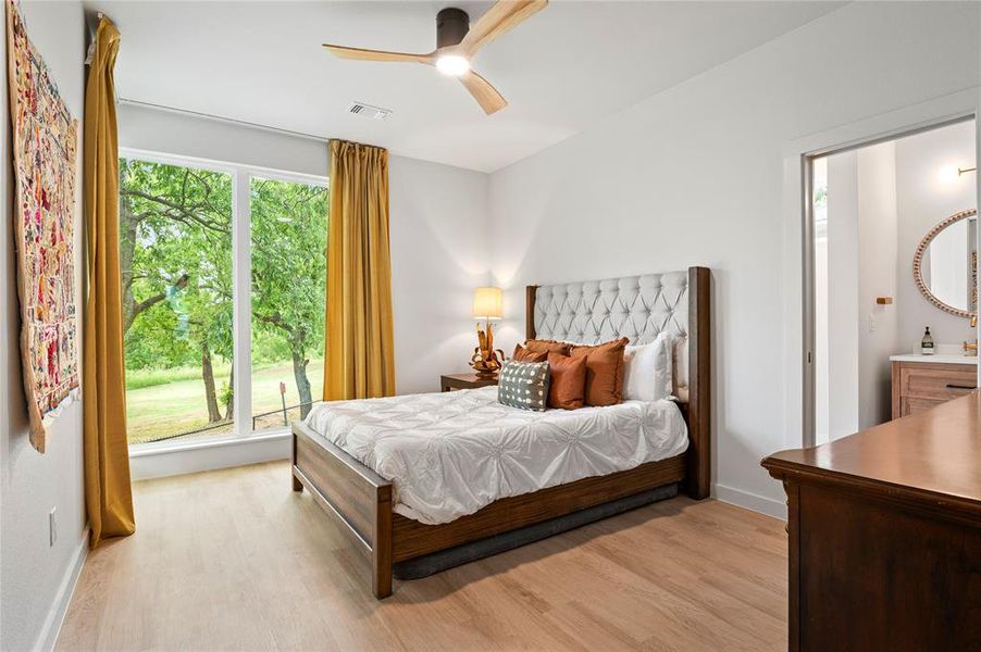 Beautiful views and natural light from the oversized windows. Bedroom with light hardwood / wood-style flooring, multiple windows, and ceiling fan.