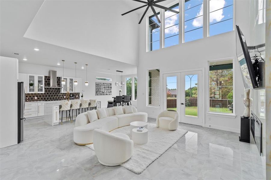 Living room featuring ceiling fan, sink, a towering ceiling, and french doors