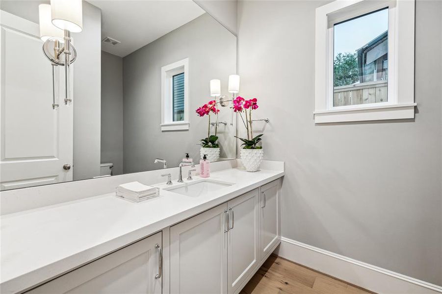 Powder Room with a Floating Cabinet, Slab Quartz Counter, Undermount Sink, 8 Inch Widespread Faucet in Chrome, Frameless Mirror and Two Savoy House 1 Bulb Wall Sconce in Polished Nickel.