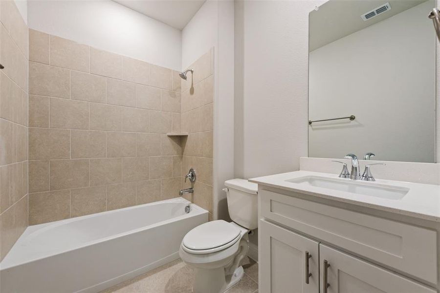 Full bathroom with tiled shower / bath combo, vanity, and toilet