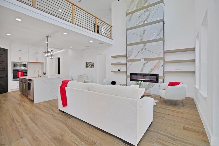 Living room featuring a fireplace, sink, light hardwood / wood-style flooring, and a notable chandelier