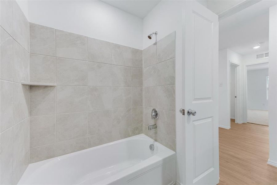 Bathroom with hardwood / wood-style floors and tiled shower / bath combo