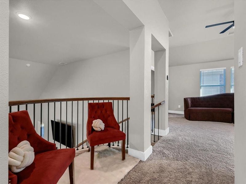 Living area featuring carpet, vaulted ceiling, and ceiling fan