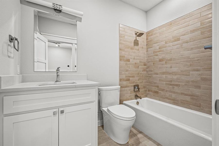 Full bathroom with vanity, toilet, tile patterned floors, and tiled shower / bath