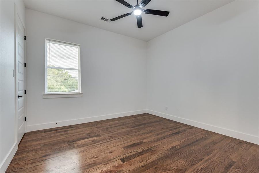 Secondary bedroom with ceiling fan and hardwood floors.