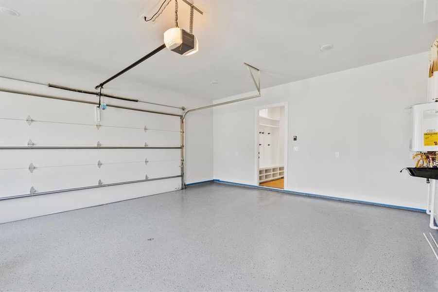 Garage featuring tankless water heater and a garage door opener