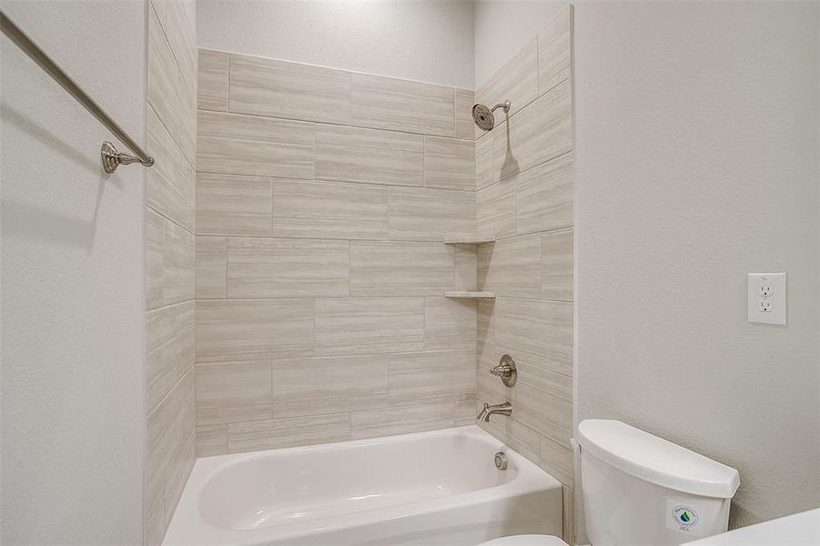 Bathroom featuring tiled shower / bath combo and toilet