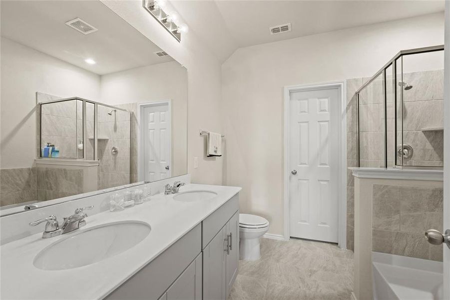 Full bathroom with tile patterned flooring, plus walk in shower, toilet, and dual bowl vanity