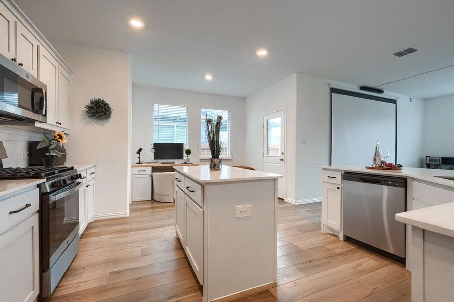 Kitchen featuring stainless steel appliances, white cabinetry, and a center island