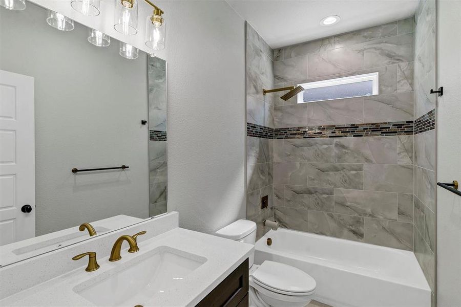 Full bathroom featuring vanity, tiled shower / bath combo, and toilet